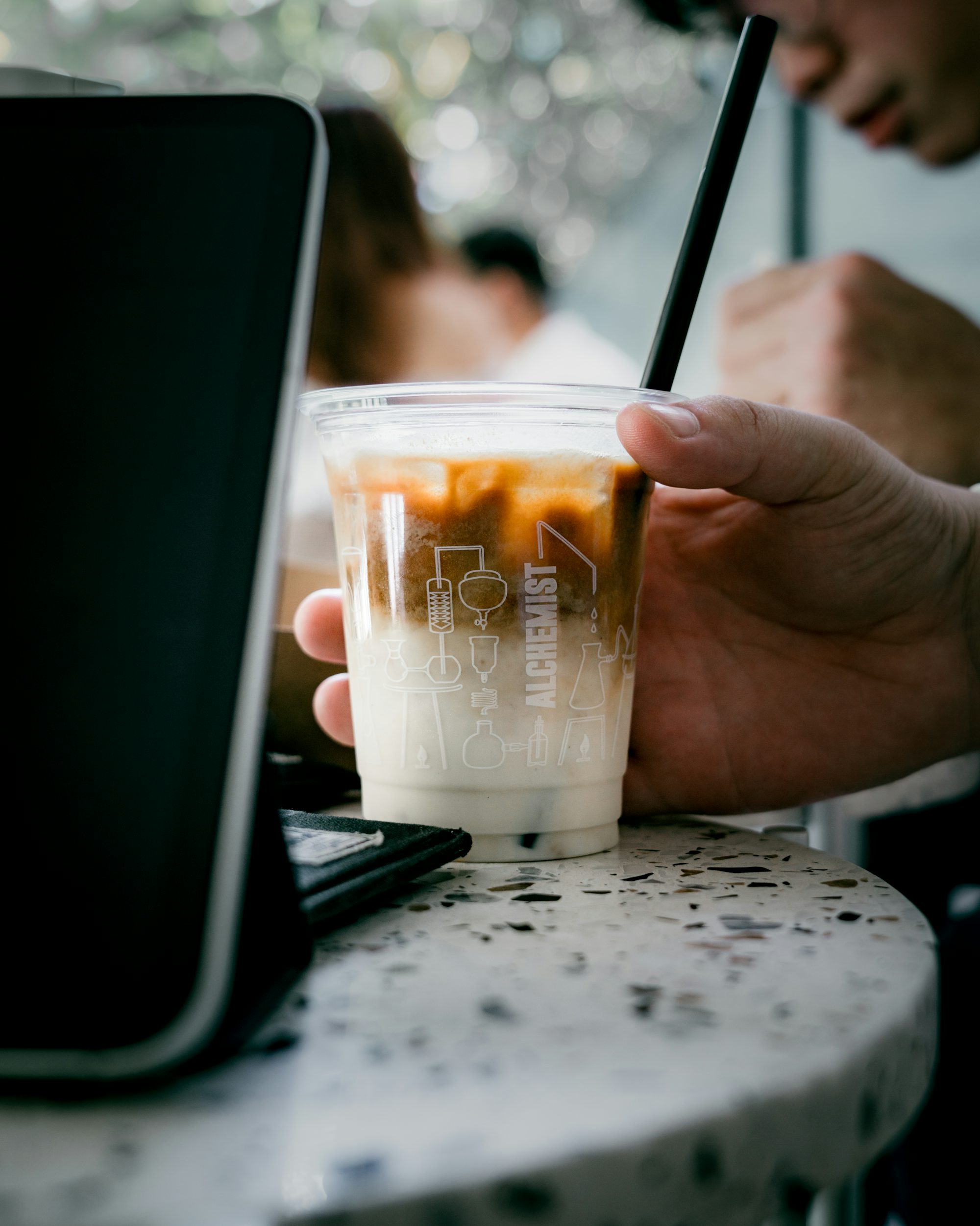 person holding clear plastic cup with brown liquid